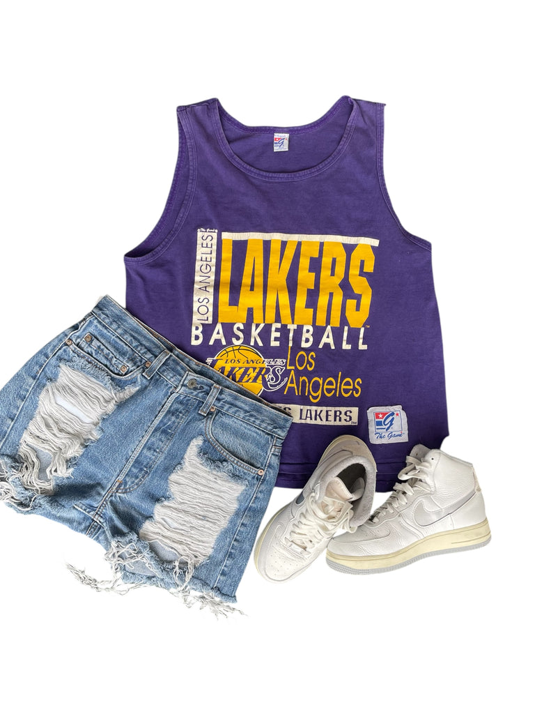 Purple Lakers tank top with denim shorts and white sneakers on a white background