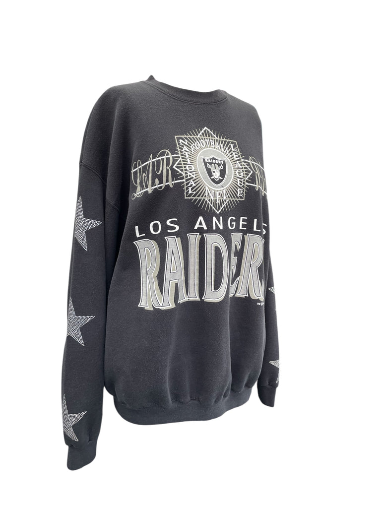 Black Los Angeles Raiders sweatshirt with white text and star designs on a white background