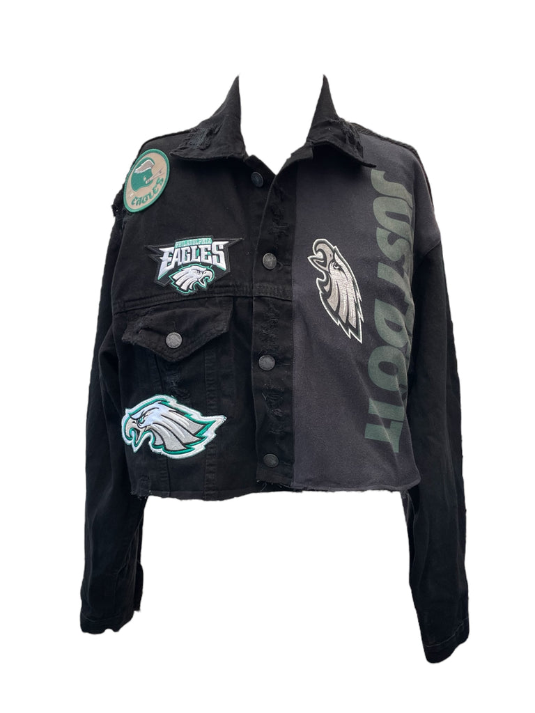 Black denim jacket with multiple patches on a white background